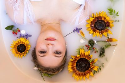 Close-up portrait of young woman with yellow flowers