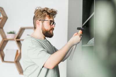 Portrait of young man wearing sunglasses while standing against wall