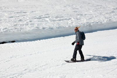 Snowboarder running down the slope in ski resort with a funny hat. winter sport and recreation, leisure outdoor activities