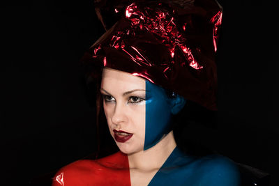 Close-up portrait of young woman against black background