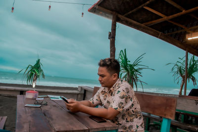 Young man looking at smartphone while sitting on table