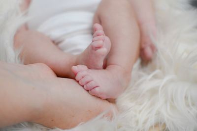 Low section of baby lying on bed