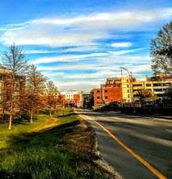 Road by buildings against sky in city