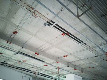 Low angle view of illuminated lighting equipment hanging on ceiling in building