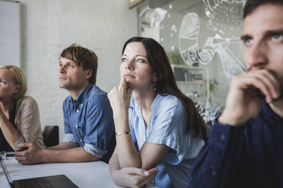 Confident creative business professionals listening while sitting in board room during meeting