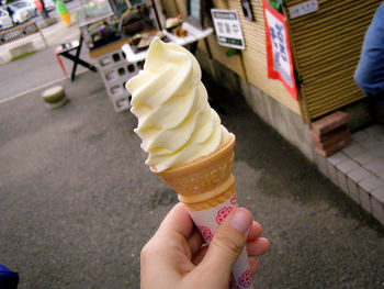 Cropped image of hand holding ice cream at street