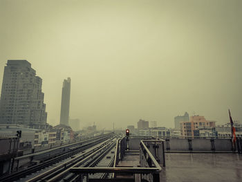 Railroad tracks in city against clear sky