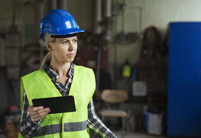 Female manual worker holding digital tablet in factory