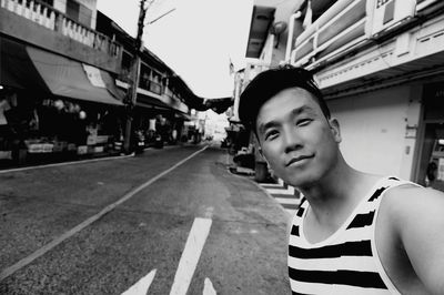 Portrait of young man on road in city