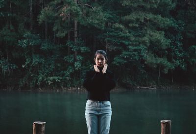 Portrait of man standing by lake against trees