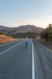 Rear view of man riding motorcycle on road against sky