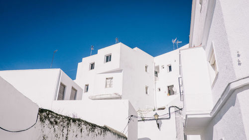 Low angle view of white residential buildings against clear blue sky