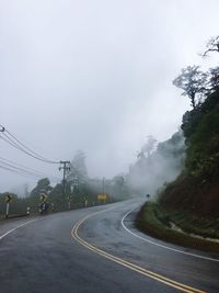 Road by trees against sky