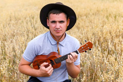 Youth star. young beautiful caucasian man playing ukulele outside. handsome hipster guy plays 