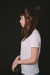 Side view of teenage girl looking away against black background
