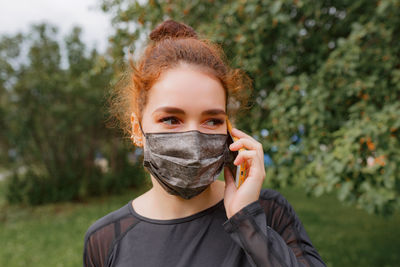 Portrait of young woman covering face and using mobile phone 