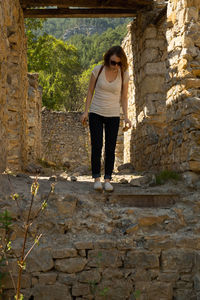 Full length of young woman standing at old ruins