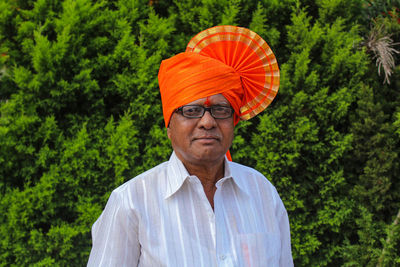 Portrait of senior man standing by trees