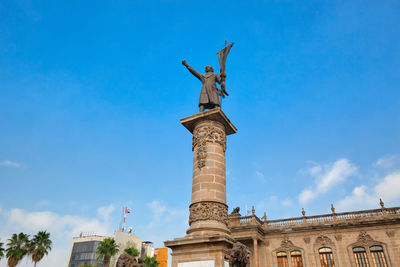 Low angle view of statue against blue sky