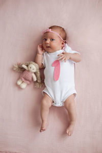 Portrait of cute baby girl sitting on bed at home