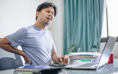 Young man using mobile phone while sitting on table