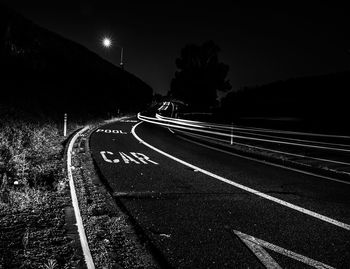 Empty road along illuminated street lights at night