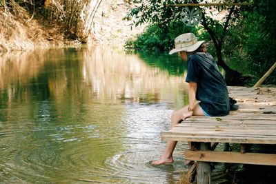 Side view of woman sitting by lake