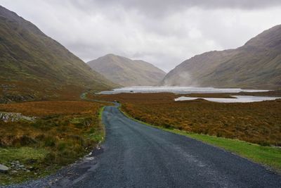 Road leading towards mountains against sky