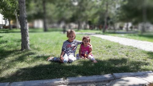 Portrait of cute siblings sitting in park