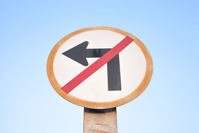 Low angle view of road sign against clear blue sky