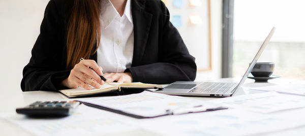 Midsection of businesswoman working on table