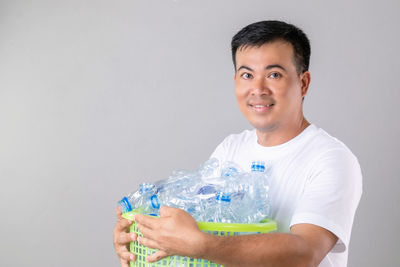 Portrait of young man holding bottle against white background