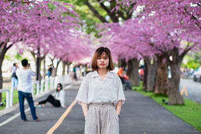 Portrait of woman standing by pink flower tree