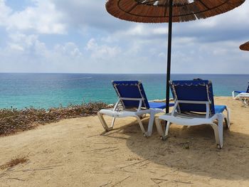 Deck chairs on beach against sky