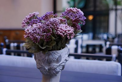 Greco-style vase/bust of a female head holding bouquet of purple flowers or lilacs. 