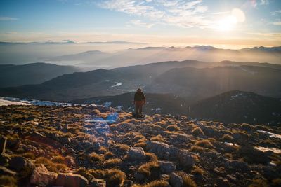 Rear view of woman looking at mountains against sky