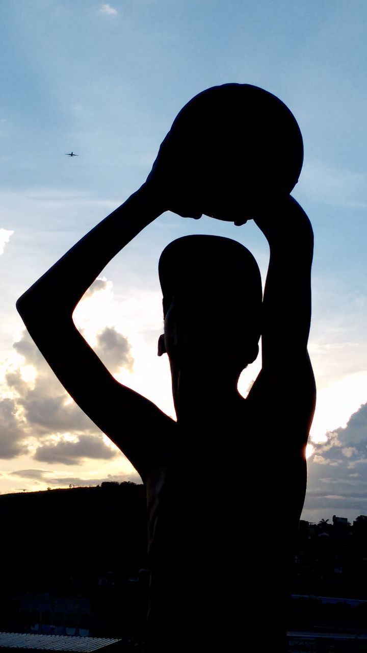 SILHOUETTE WOMAN WITH ARMS OUTSTRETCHED STANDING AGAINST SKY