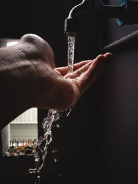Cropped image of person washing hand from faucet