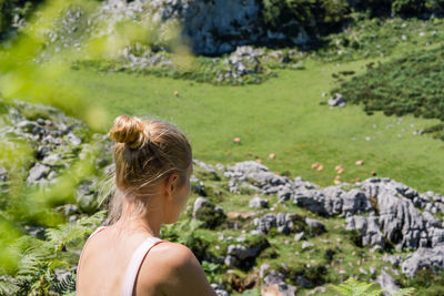 Woman sitting down on the mountain overlooking field full of cows