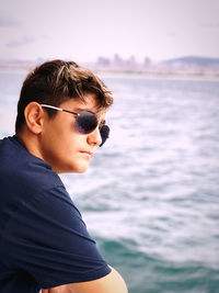 Portrait of young man standing by sea against sky