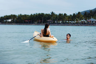 Rear view of woman kayaking in lake