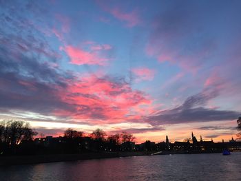 Scenic view of river against cloudy sky at sunset