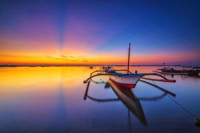 Boat moored on beach against sky during sunset