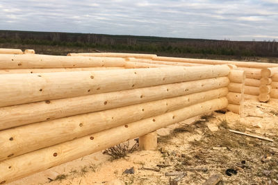 Stack of wood on field against sky