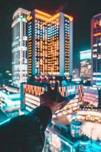 Close-up of hand on illuminated cityscape at night