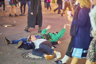 Drunk men lying on road at amusement park during night