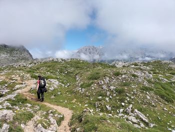 Rear view of man walking on mountain against sky