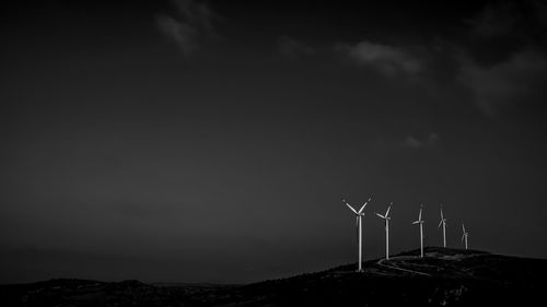 Windmill on landscape against sky at night