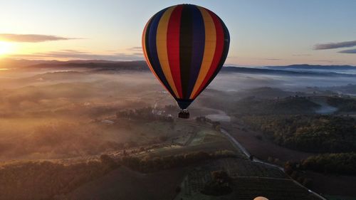 Hot air balloon flying over landscape against sky during sunset