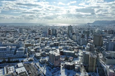 Aerial view of cityscape against cloudy sky
